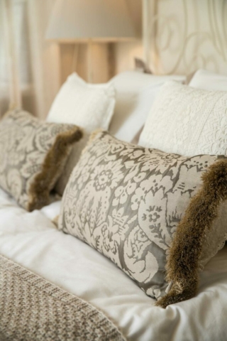 Šedé dekorativní polštáře v posteli